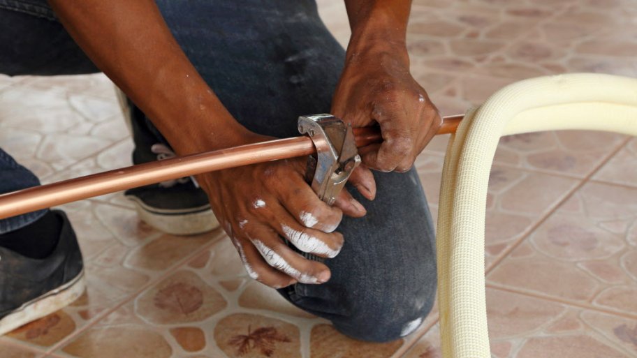 man cutting into copper pipe